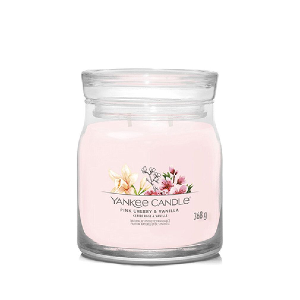 Candela in vetro rosa con coperchio. Etichetta con fiori, scritta 'Yankee Candle', 'Pink Cherry & Vanilla' e indicazione del peso.