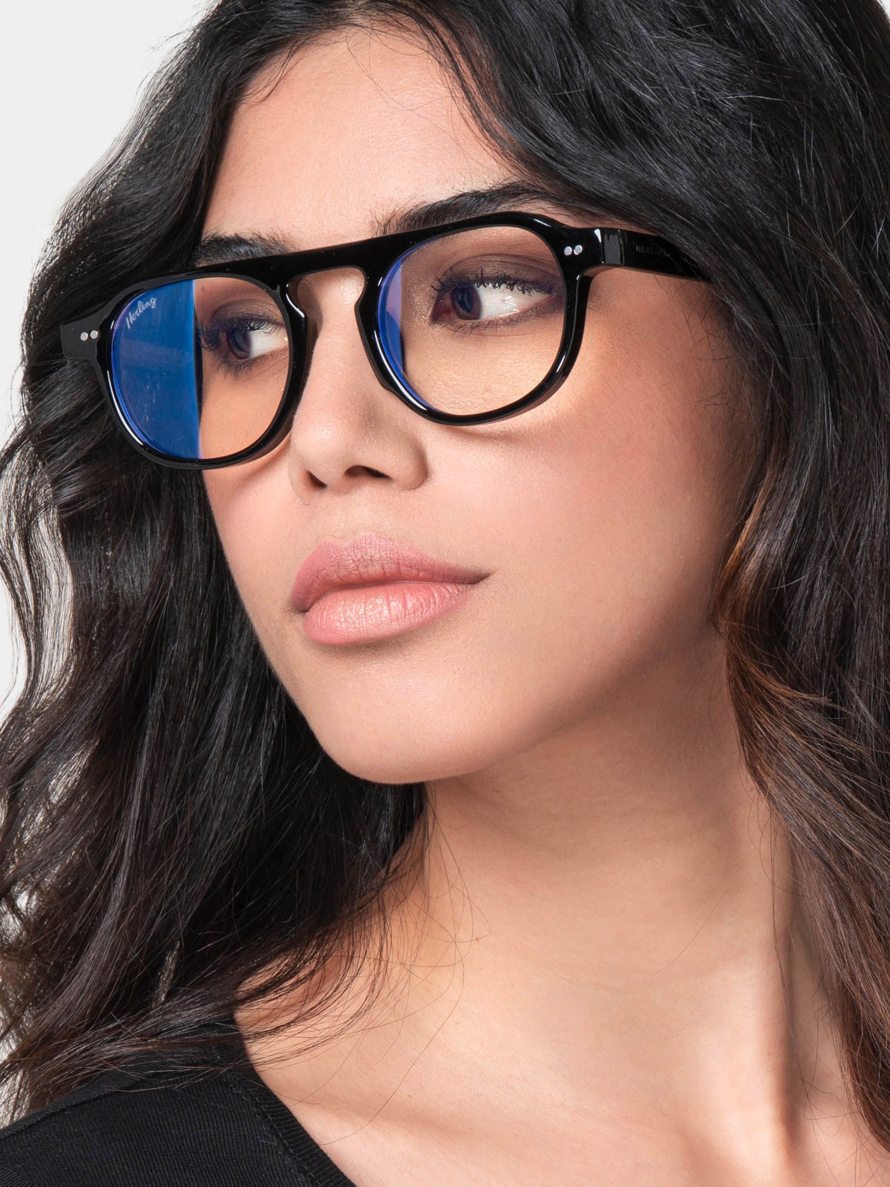 Donna con occhiali neri. Lenti blu. Montatura con ponte e aste. Logo "Herling" visibile.
