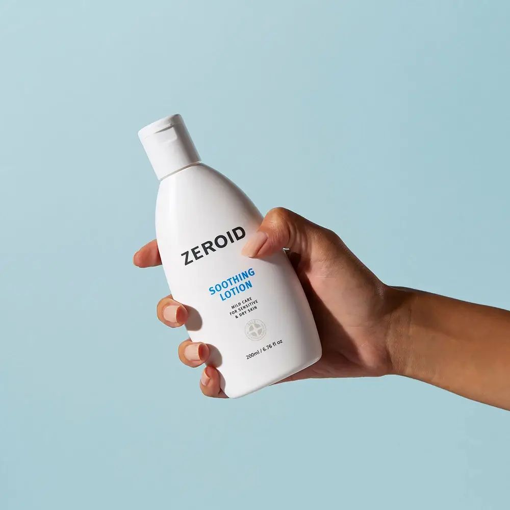 Flacone bianco ZEROID Soothing Lotion in mano. Logo e testo blu. Contiene 200ml/6.76 fl oz.