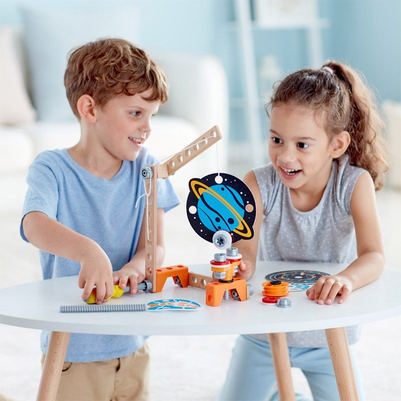 Due bambini giocano con un giocattolo da costruzione. Il giocattolo è in legno e plastica, con decorazione pianeta.