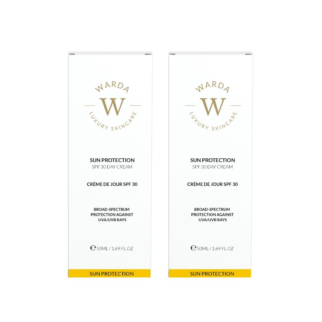 Due confezioni bianche con logo dorato. Crema giorno SPF 30. Testo: Broad Spectrum Protection contro i raggi UVA/UVB.