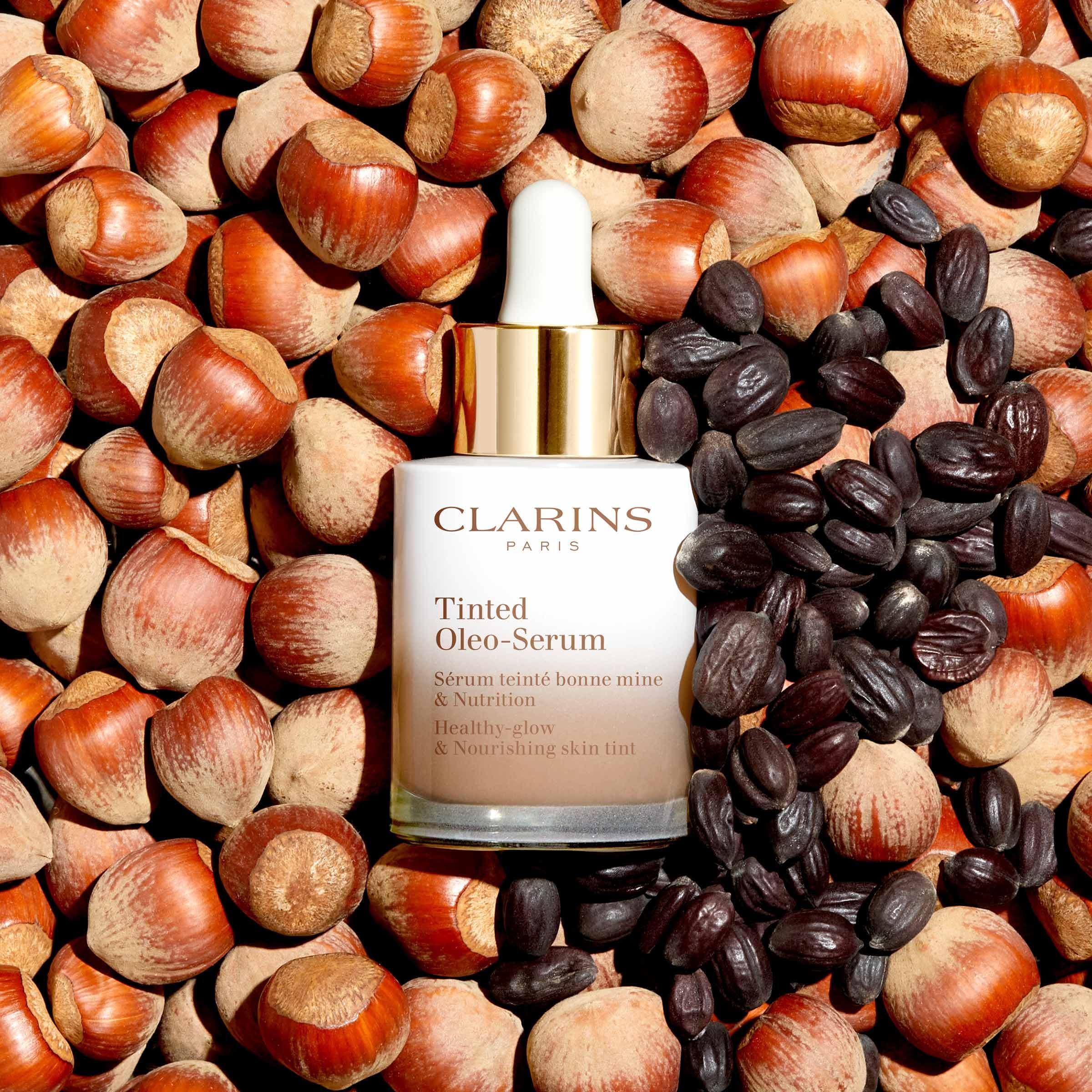 Flacone Clarins Tinted Oleo-Serum su nocciole e semi. Flacone in vetro sfumato bianco-marrone, tappo dorato e contagocce bianco.