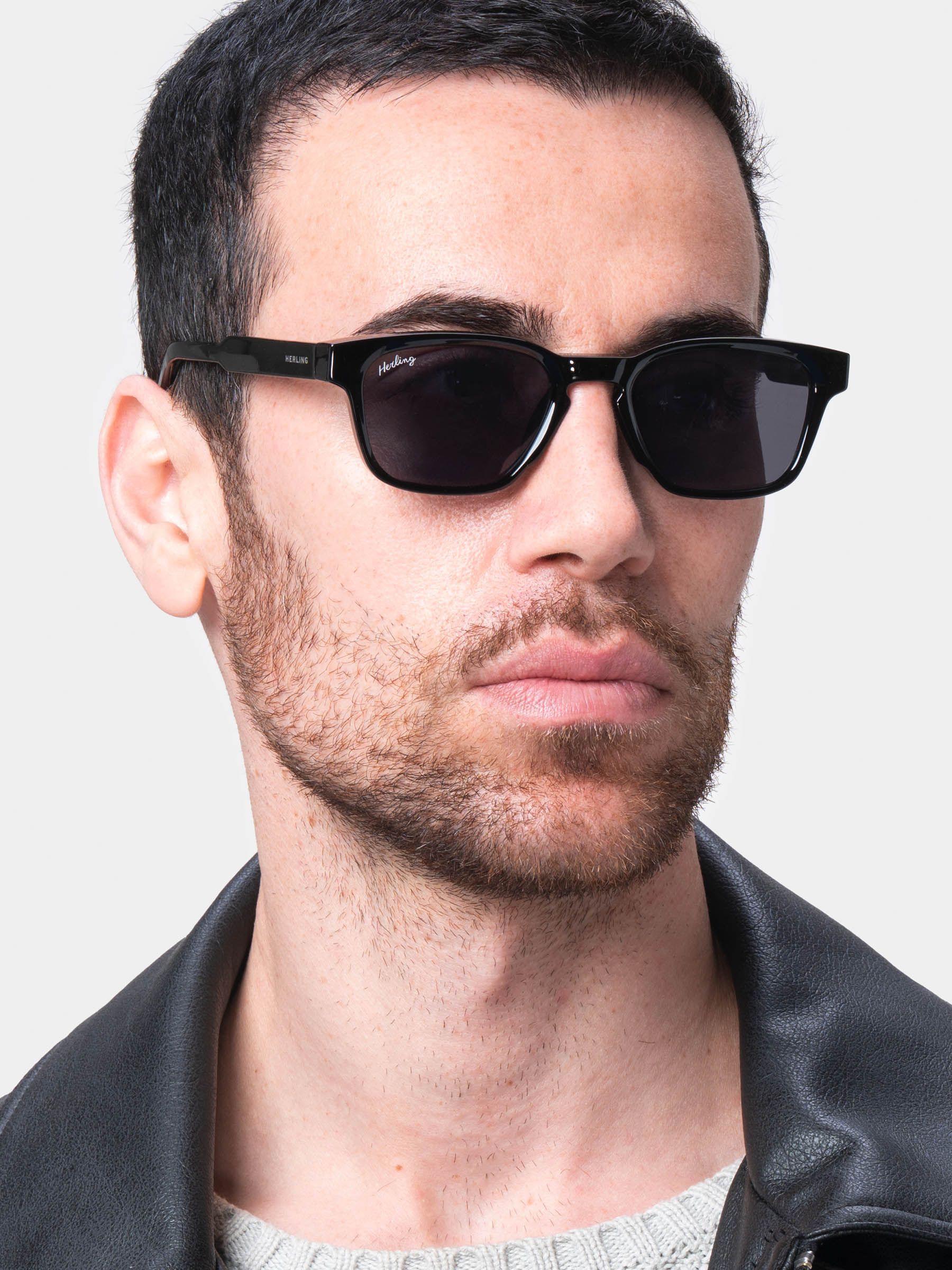 Uomo con occhiali da sole neri. Il marchio Herling è visibile sull'asta.
