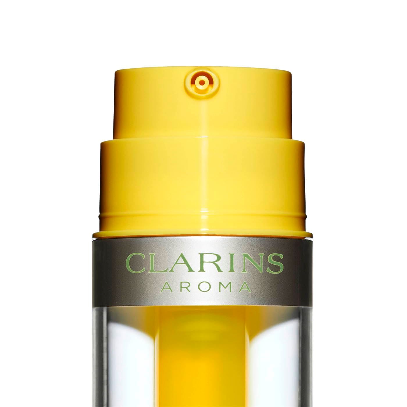 Primo piano dell'emulsione olio Clarins Plant Gold. Pompa gialla, anello argentato con testo. Testo: Clarins Aroma.