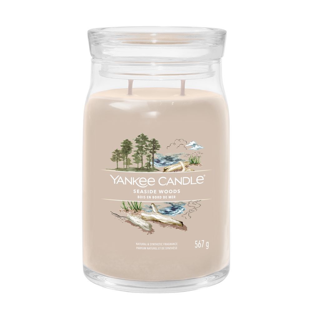 Contenitore di vetro con coperchio. Scritta: Yankee Candle Seaside Woods. 567 g. Illustrazione di spiaggia e alberi.
