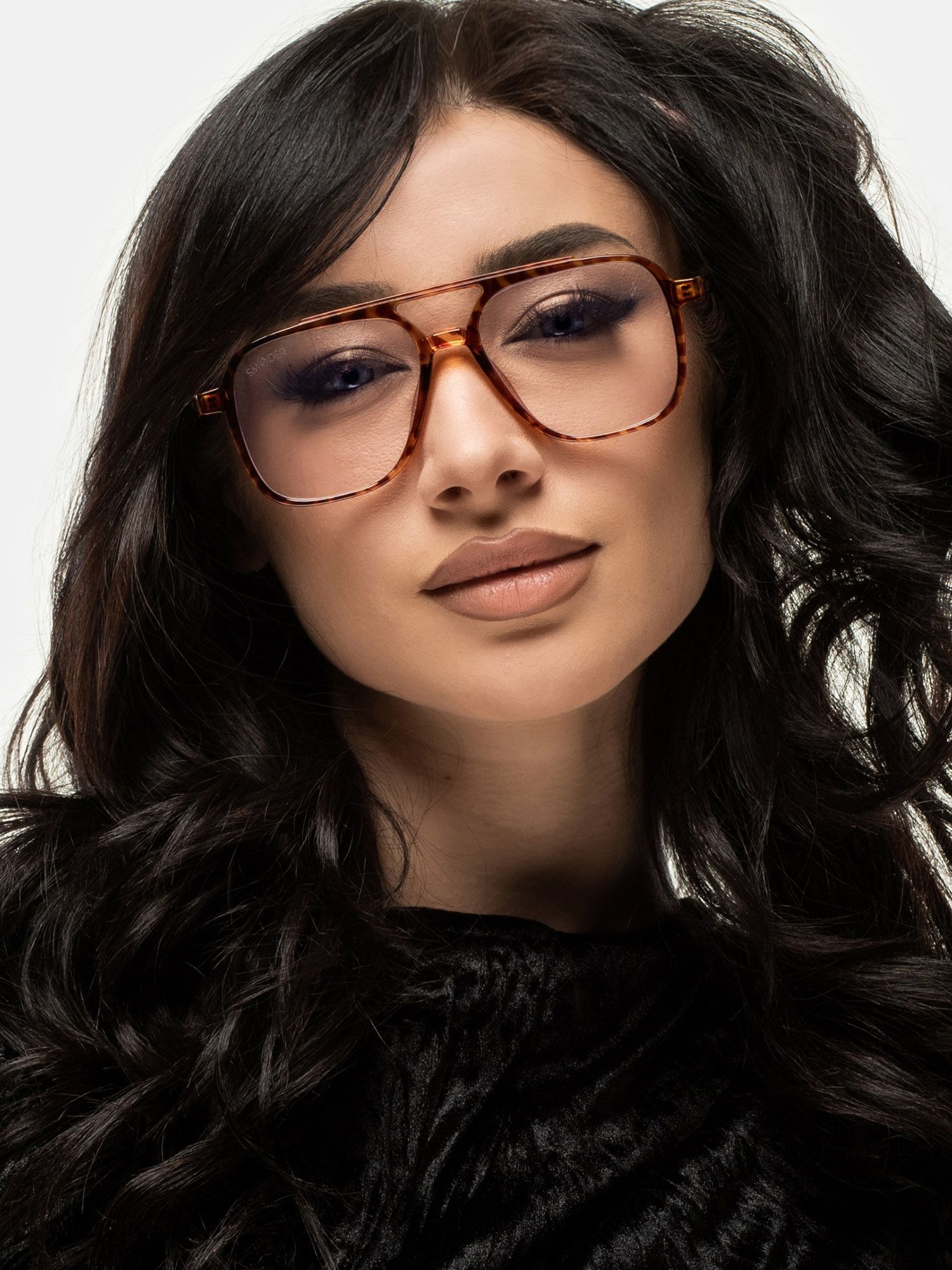 Donna con occhiali marroni a fantasia tartarugata. Lenti rettangolari, doppio ponte. Design unisex. Primo piano.