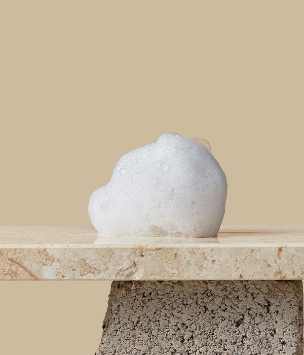 Schiuma bianca su una superficie. Sfondo beige. La schiuma ha una forma irregolare.