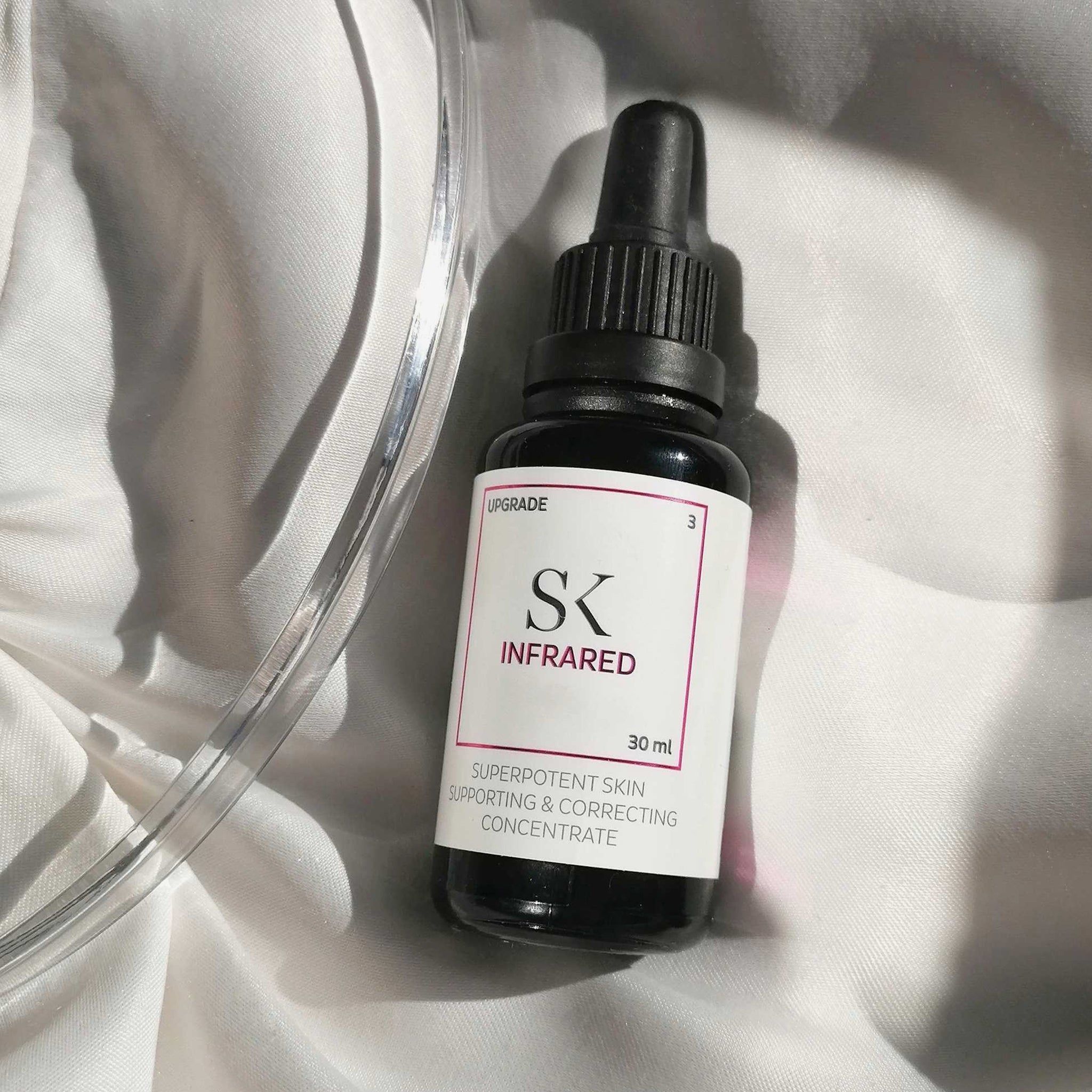Flacone di vetro scuro con tappo e pipetta neri. Etichetta "SK INFRARED" e testo. 30 ml. Su tessuto bianco.