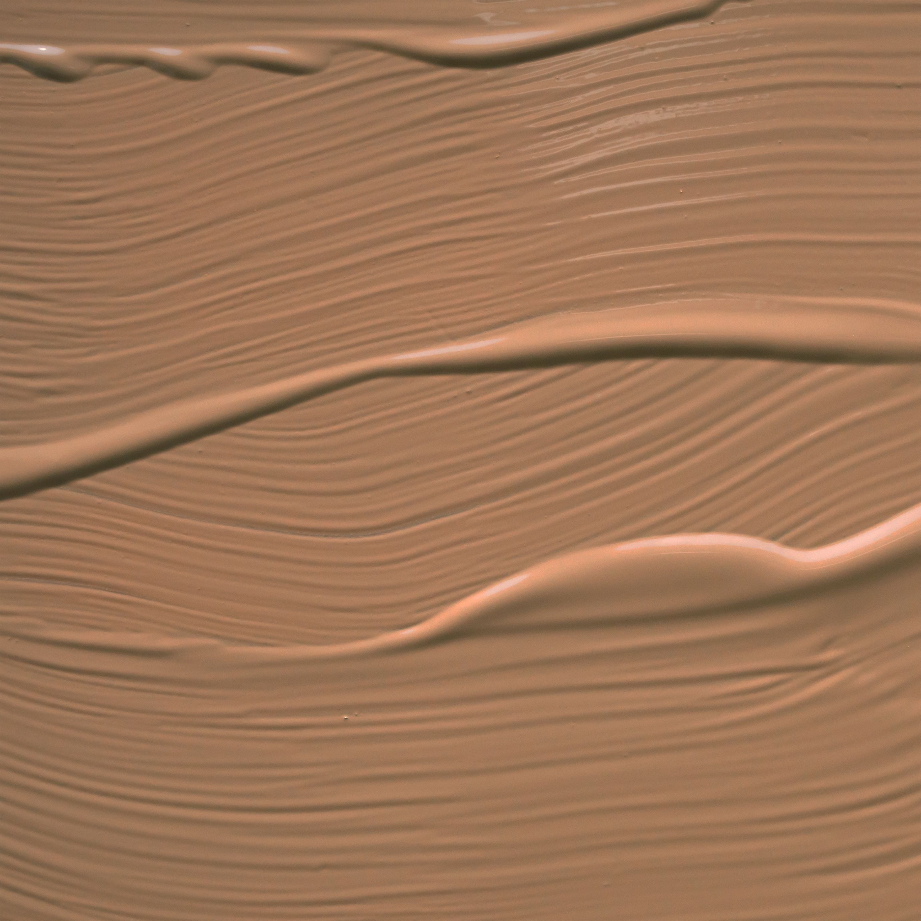 Un campione di texture di fondotinta liquido, tonalità marrone chiaro, applicato con un pennello.