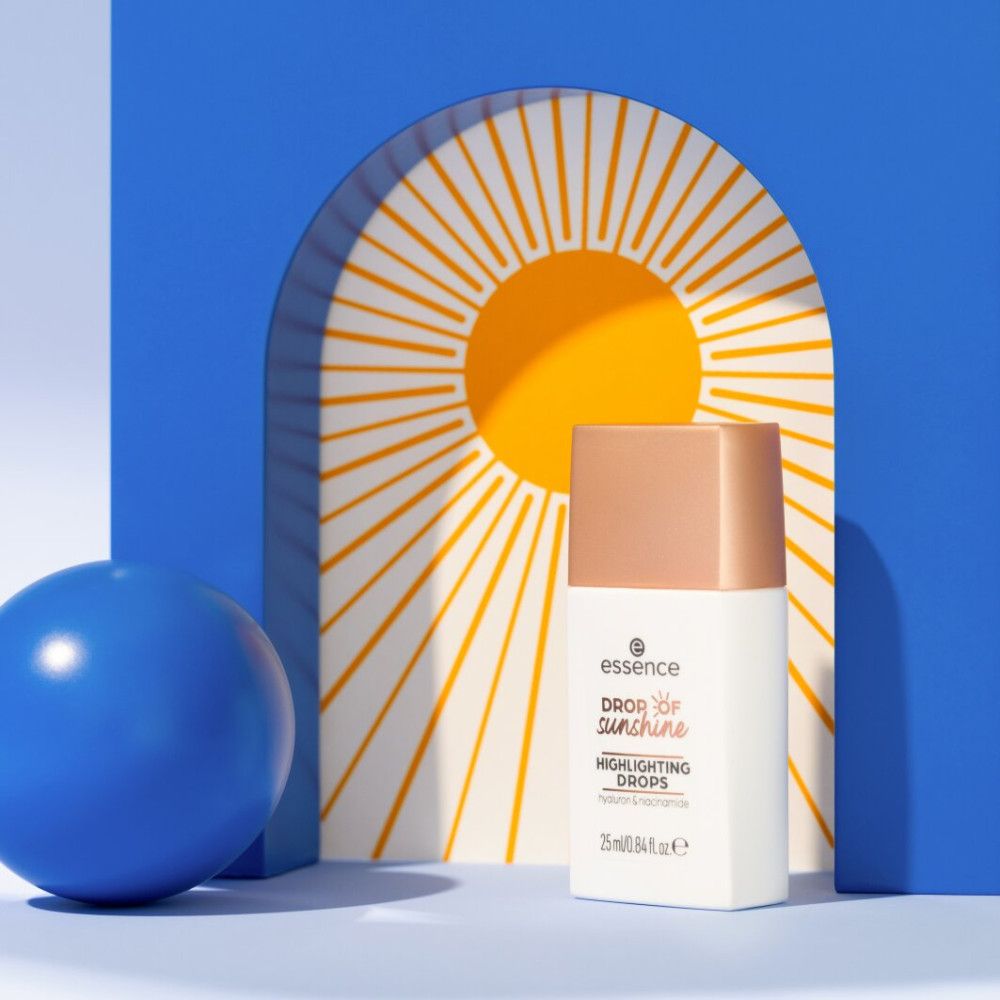 Flacone di prodotto su sfondo blu con sole e sfera. Scritta: essence, Drop of Sunshine, Highlighting Drops, Hyaluron & Niacinamide. 25 ml/0.84 fl. oz. e.