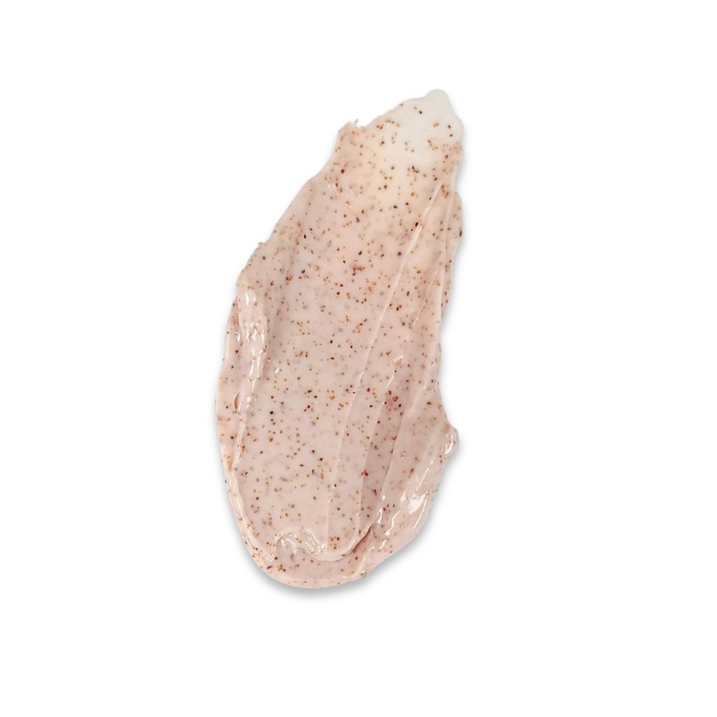 Macchia di scrub cremoso chiaro con piccole particelle scure su sfondo bianco.