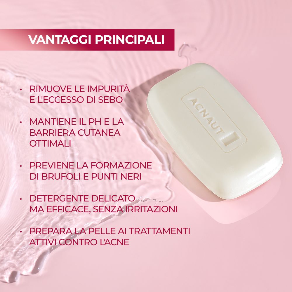 Sapone rettangolare con 'ACNAUT' in rilievo. Appoggiato su una superficie rosa con gocce d'acqua.
