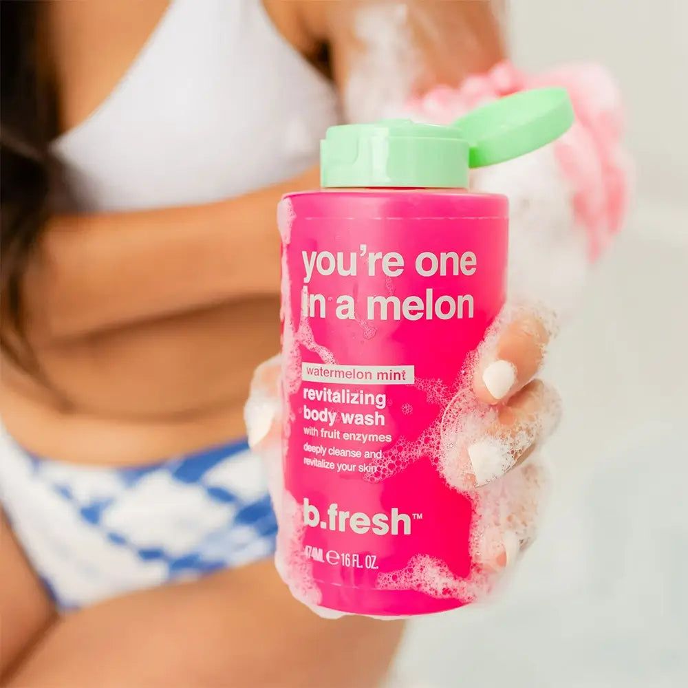 Flacone di gel doccia rosa con tappo verde. Scritta: "you're one in a melon". Marchio: b.fresh. Persona tiene flacone e spugna.