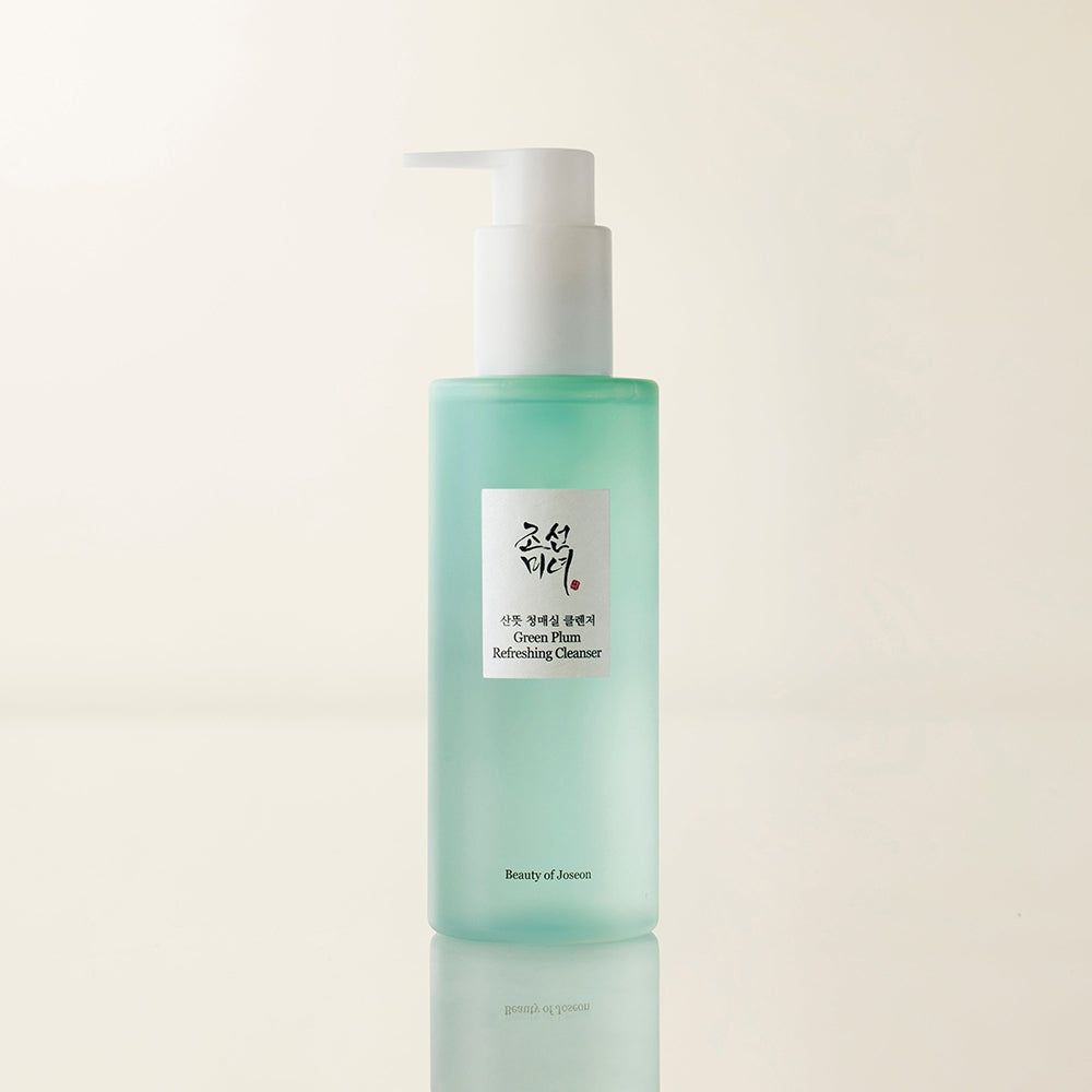 Flacone spray verde con etichetta 'Green Plum Refreshing Cleanser'.