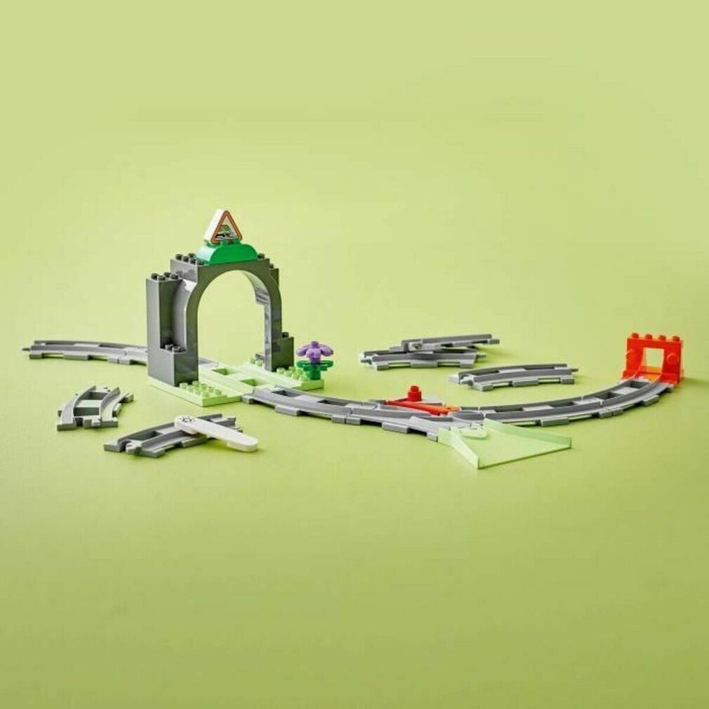 Set di espansione LEGO Duplo con tunnel, binari e accessori. Sfondo verde. Tunnel grigio, binari.