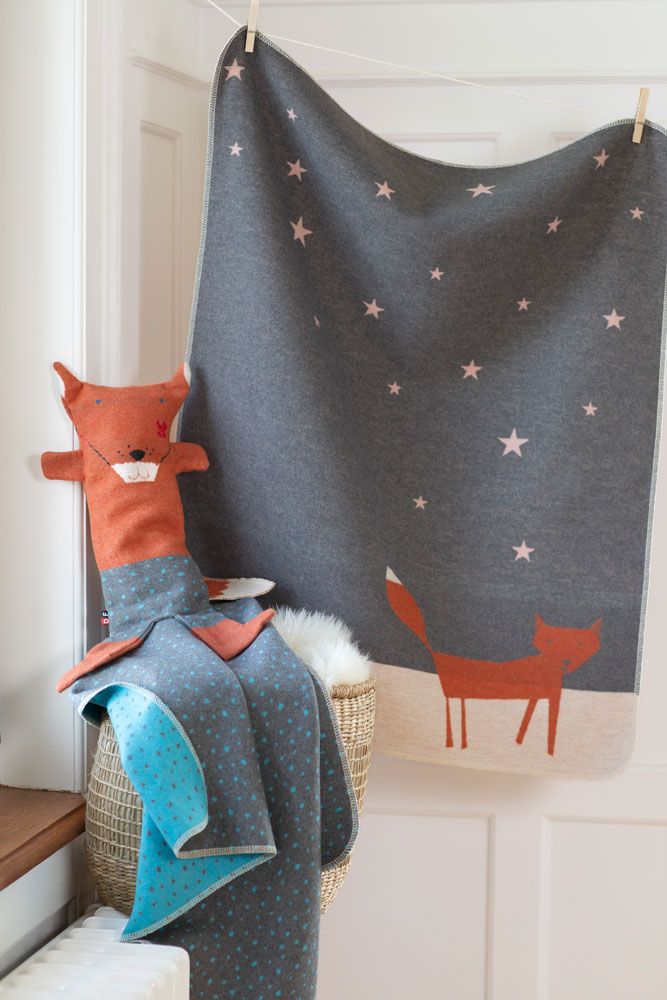 Coperta grigia con volpe arancione e stelle rosa, appesa.