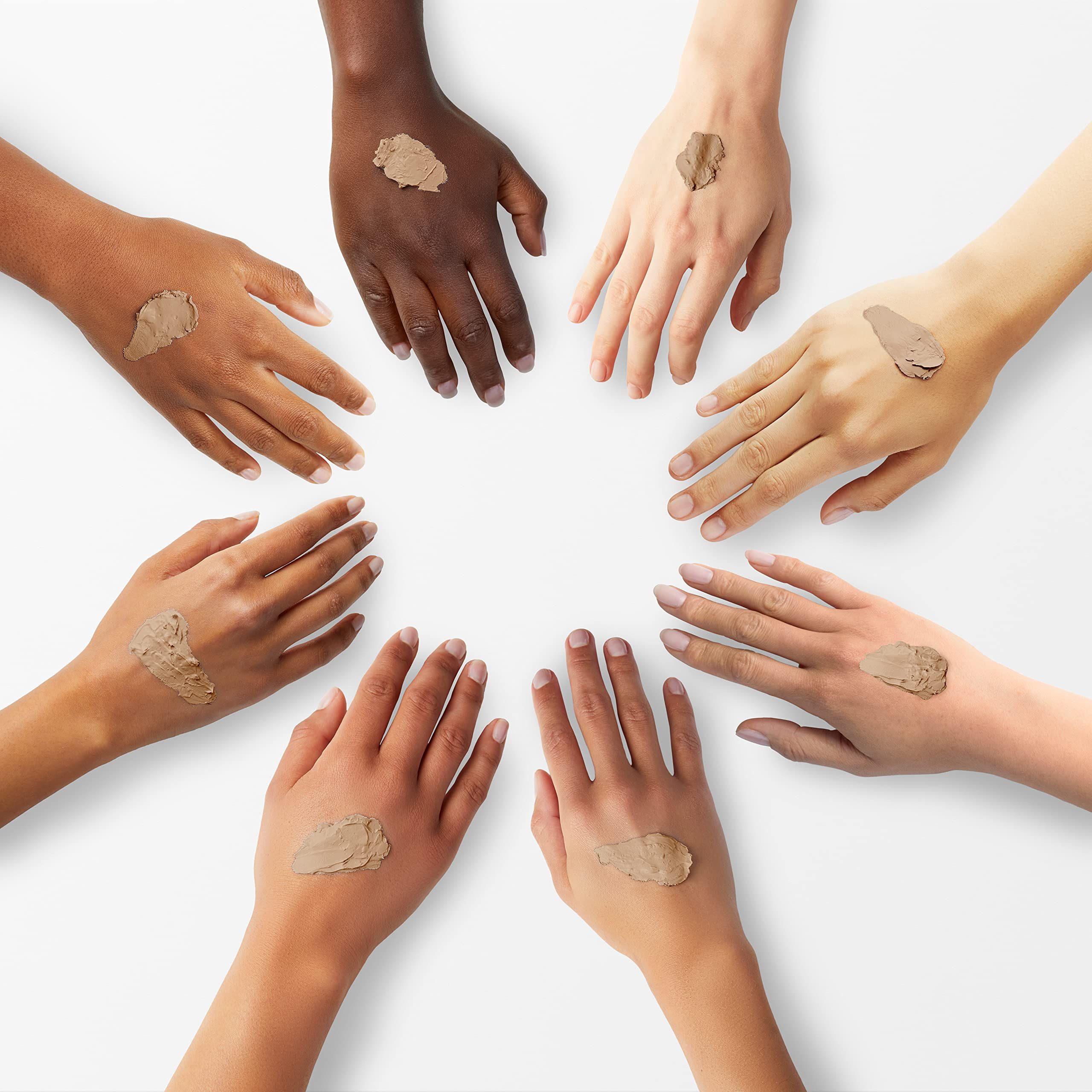 Sette mani di diverse tonalità di pelle, ciascuna con una macchia di correttore sul dorso.