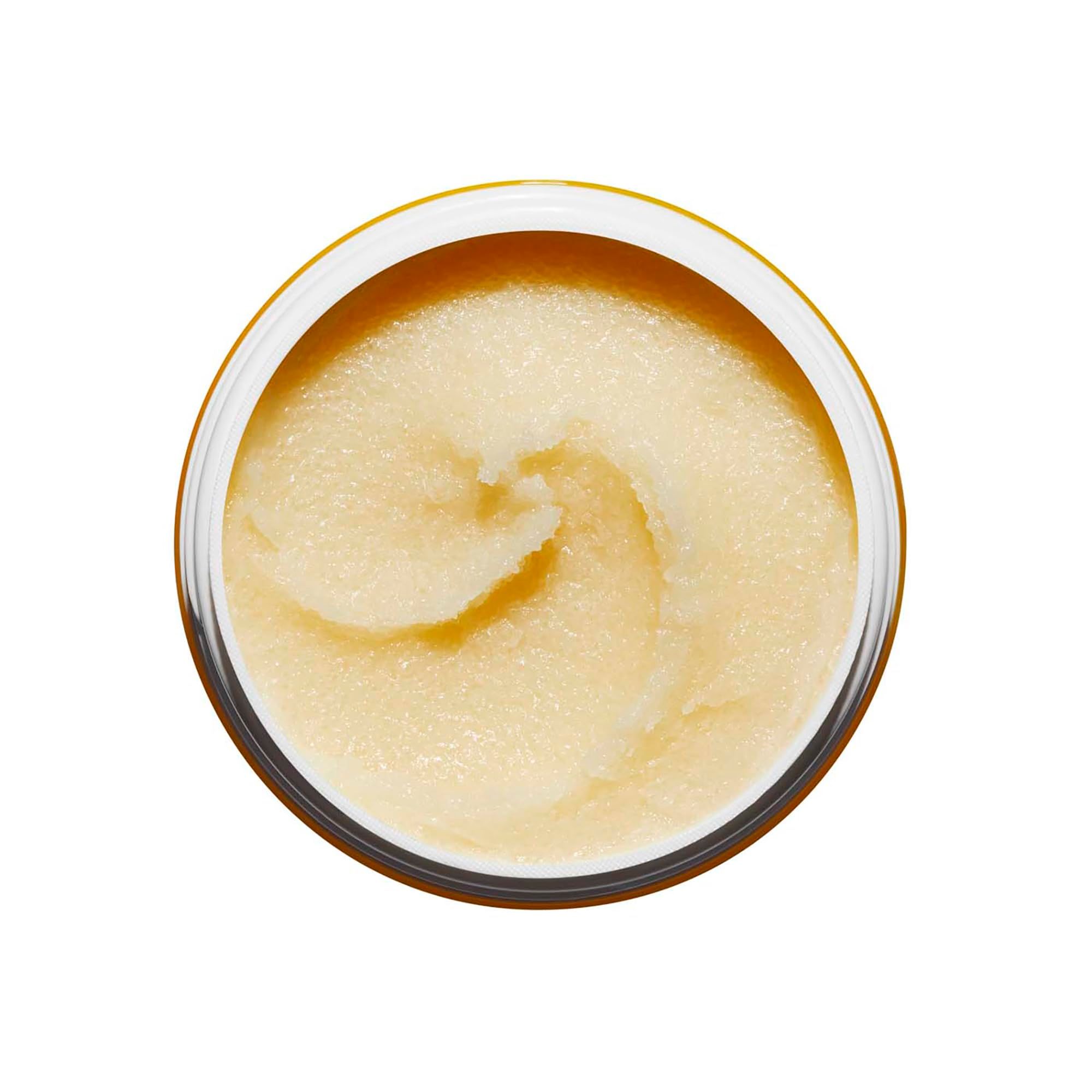 Vista dall'alto del prodotto. Texture giallastra e granulosa. Scritta: Clarins Aroma, Gommage au Sucre Tonic, Tonic Sugar Polisher.