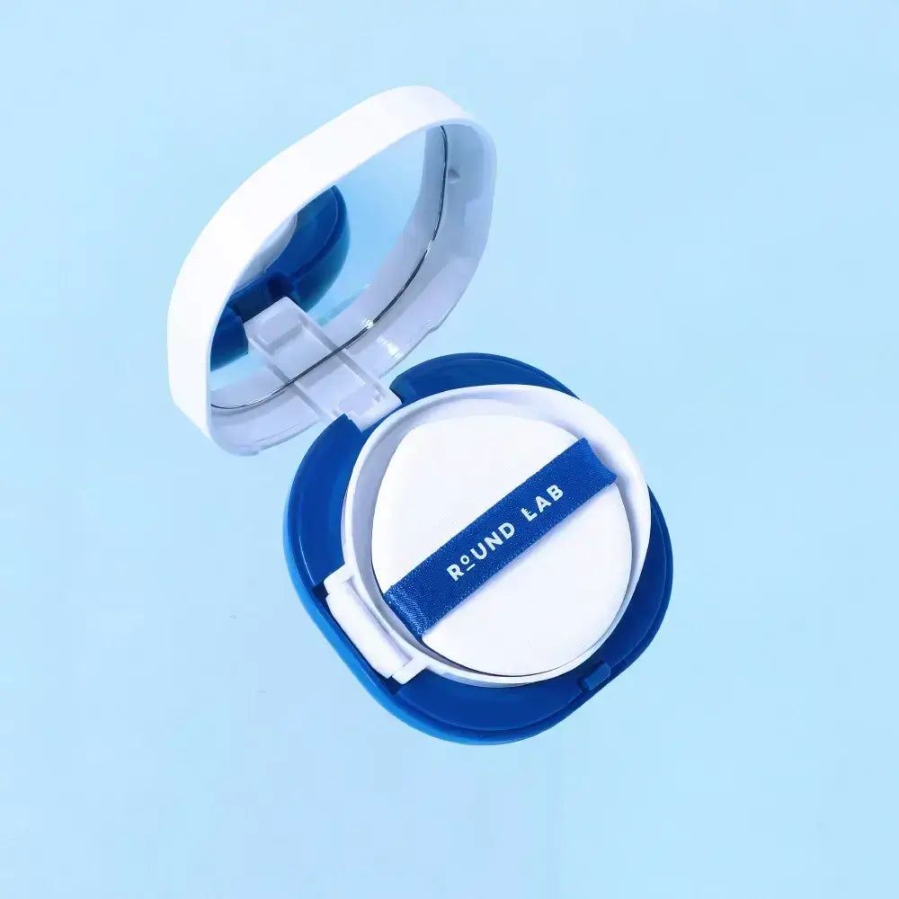Cuscino solare Round Lab aperto. Spugnetta bianca con nastro blu con logo, nel contenitore blu e bianco.