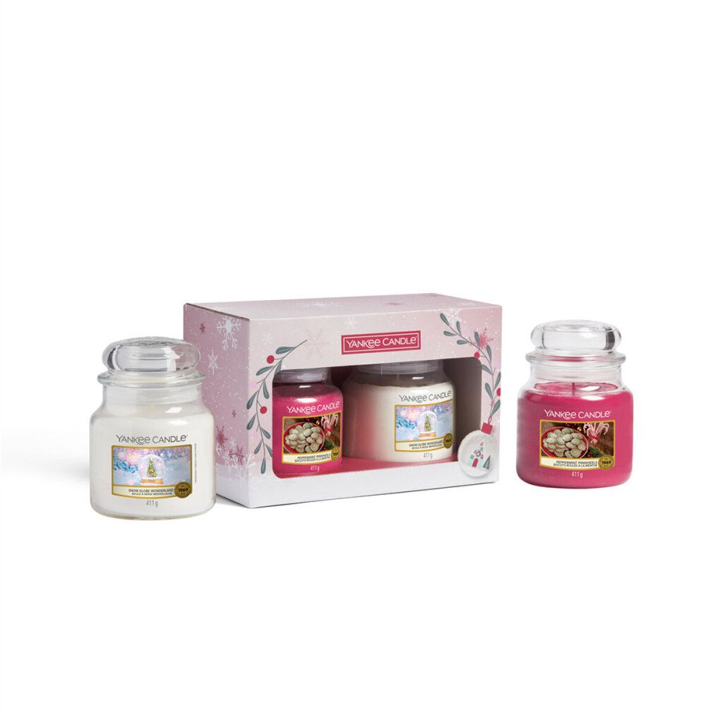 Confezione regalo con due candele in vetro in scatola. Altre due candele accanto. Logo: Yankee Candle. Rosa, bianco. Decorazioni natalizie.