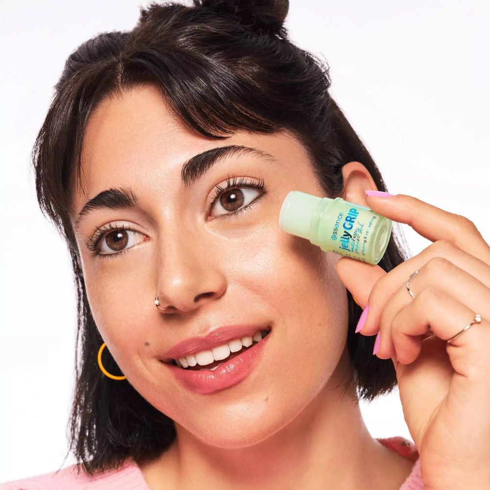 Donna tiene stick primer verde vicino all'occhio. Scritta: essence jelly GRIP under eye primer stick.