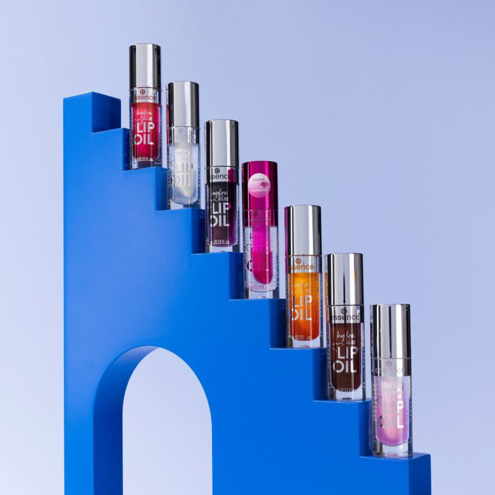 Diversi flaconi di lucidalabbra su una scala blu. Sono visibili diversi colori.