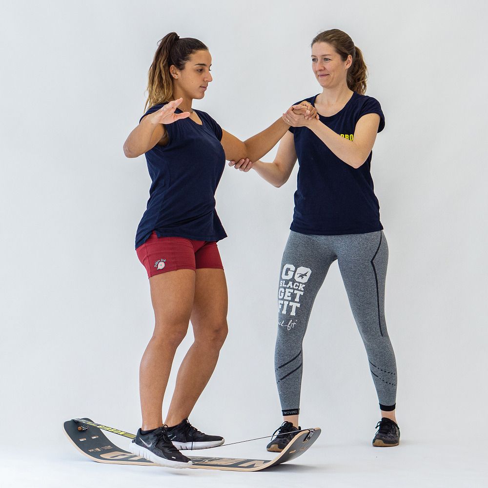 Due persone si allenano con GIBOARD SET - CAESAR JIB, una persona sulla tavola, l'altra tiene la mano.