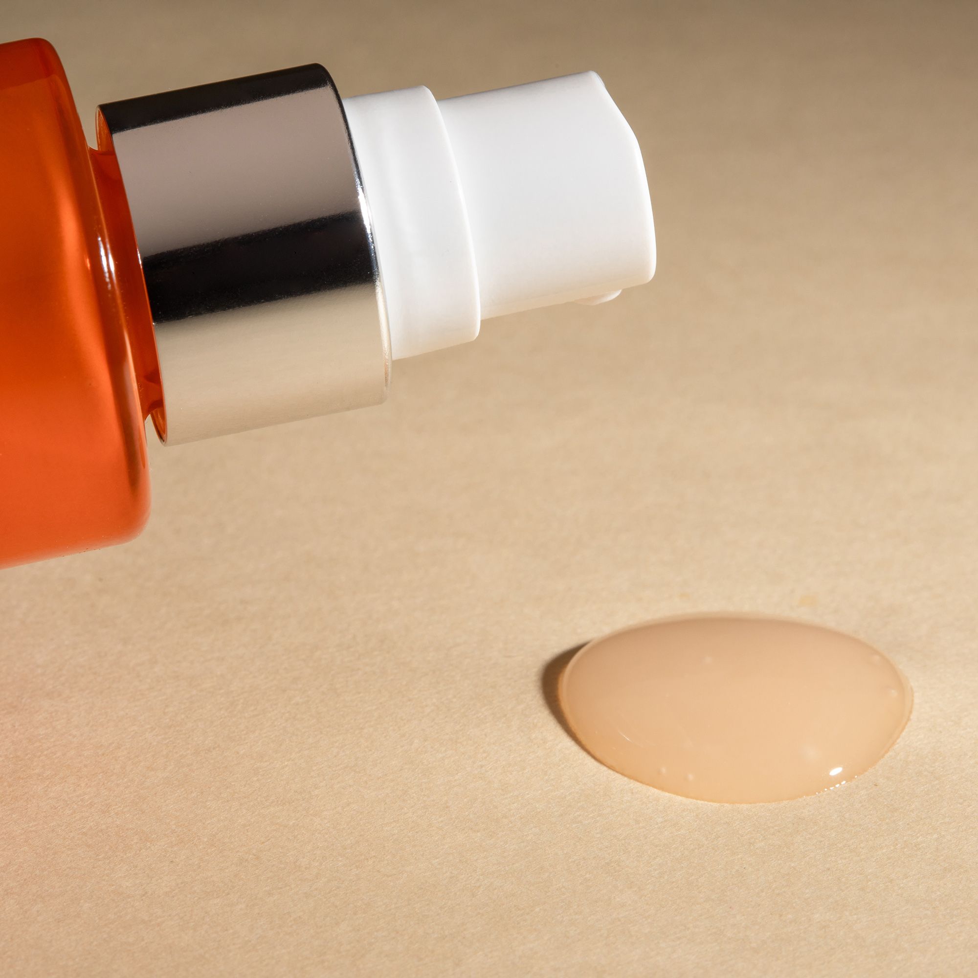 Goccia di siero. Goccia di siero su sfondo beige. Flacone con vaporizzatore sullo sfondo.