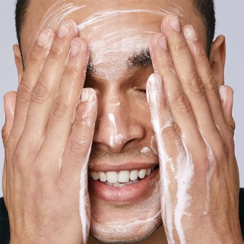 Uomo che si lava il viso con schiuma. Occhi chiusi, mani coperte di schiuma.