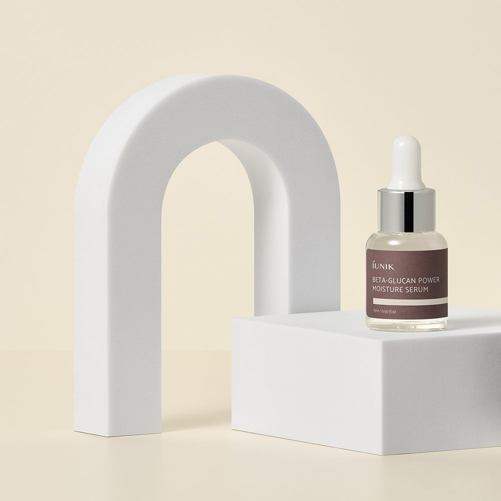 Flacone di siero con pipetta. Etichetta marrone con testo: Beta-Glucan Power Moisture Serum. Su piedistallo bianco.