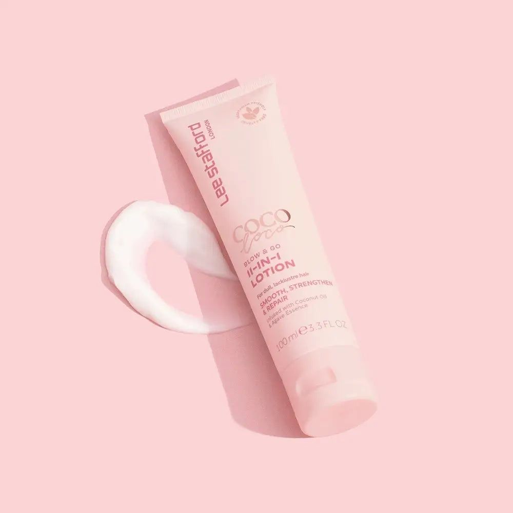 Tubo rosa Lee Stafford Coco Loco Blow & Go Lozione 11-in-1 con una striscia di lozione accanto.
