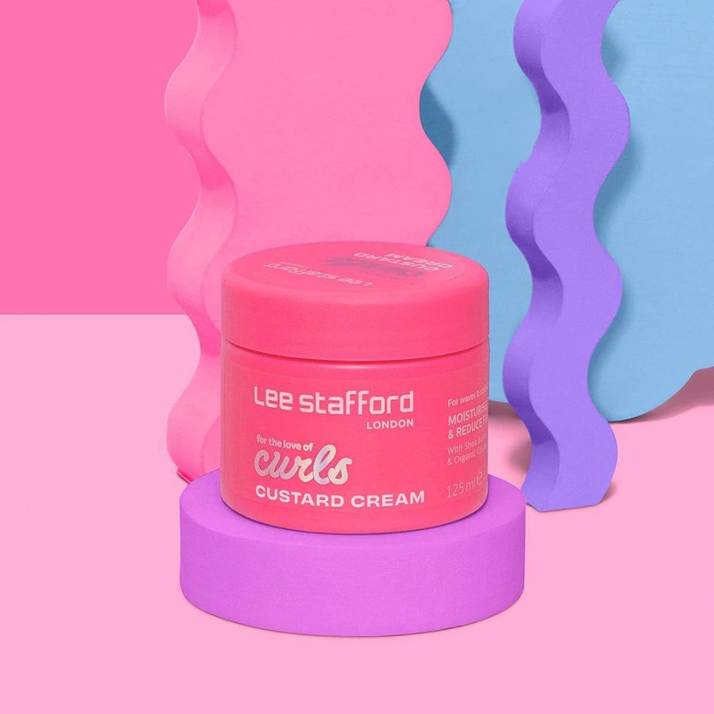 Lee Stafford Curls Custard Cream su piedistallo viola, davanti a onde colorate.