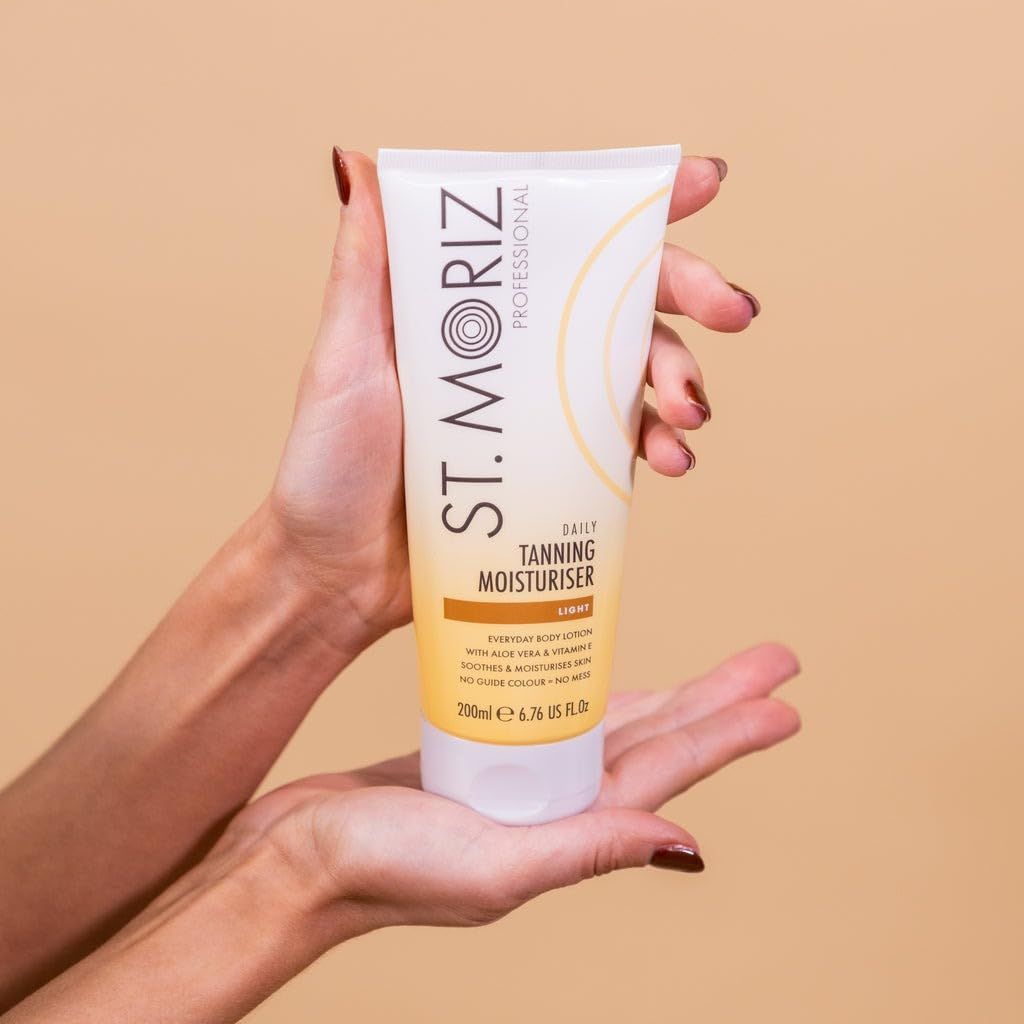 Mani che tengono la lozione St. Moriz. Tubo bianco con dettagli gialli. Scritta: Daily Tanning Moisturiser, Light.