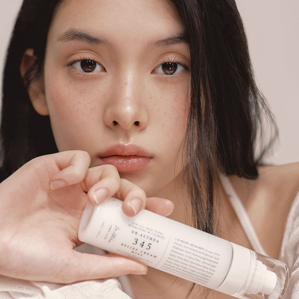 Una donna tiene una bottiglia spray bianca di Dr. Althea 345 Relief Cream Mist.
