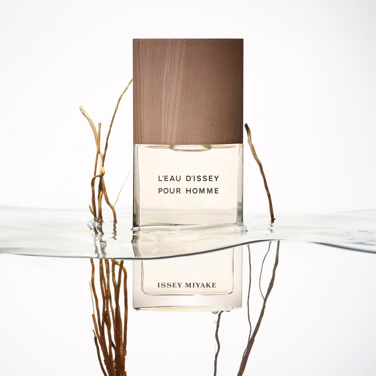 Flacone in acqua con rami. Scritta: L'EAU D'ISSEY POUR HOMME, ISSEY MIYAKE.