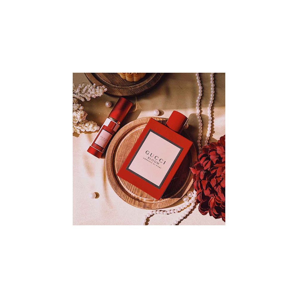 Flacone rosso e rossetto su vassoio di legno. Gucci Bloom Ambrosia di Fiori. Decorazione con perle e fiori.