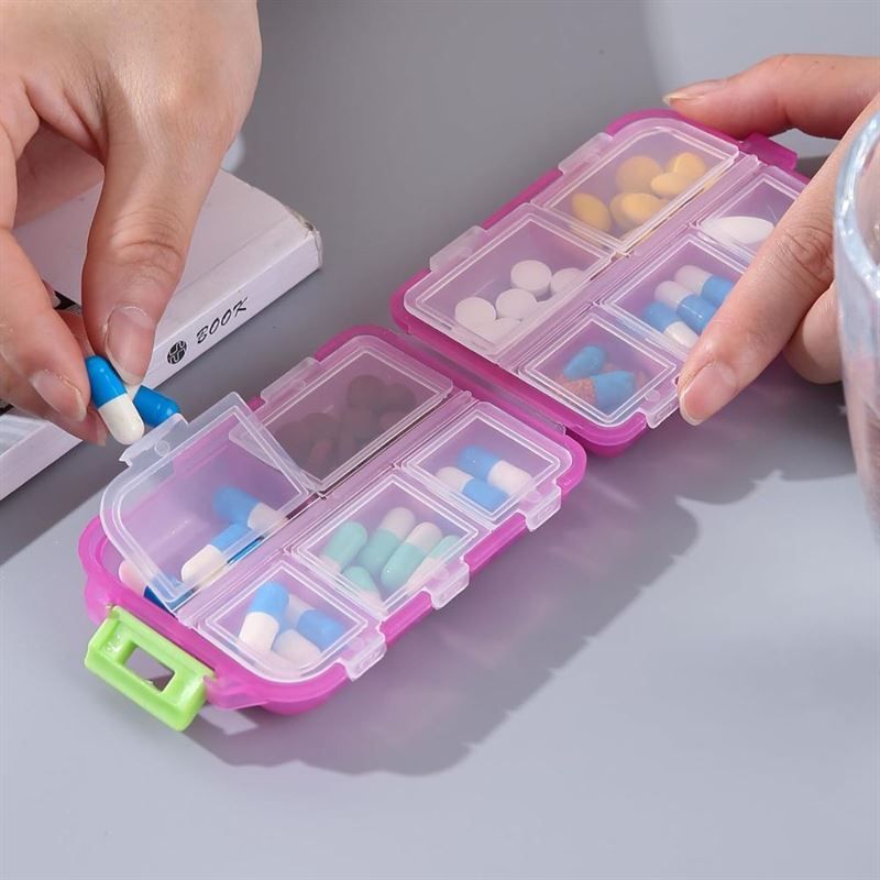 Portapillole rosa a 8 scomparti, riempito con varie pillole e capsule.