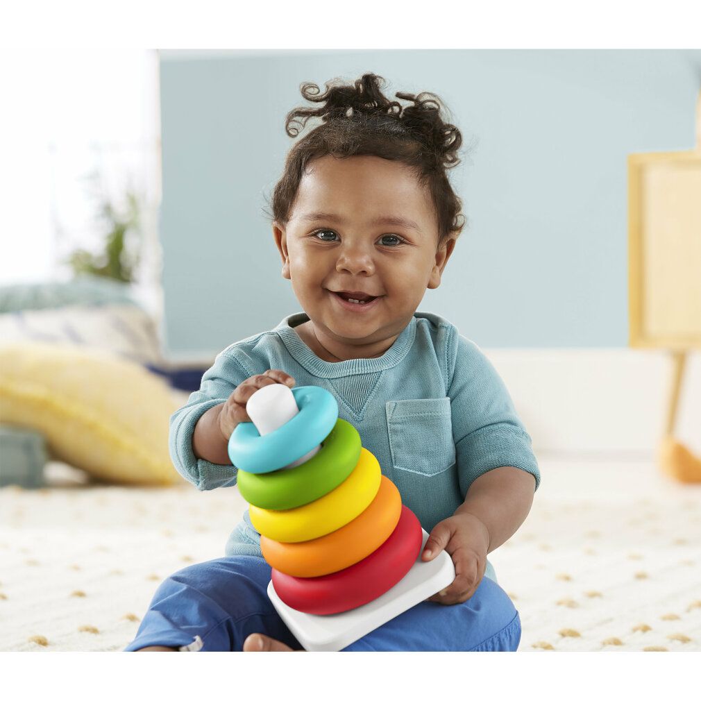 Bambino che tiene una torre di anelli impilabili. Colori: blu, verde, giallo, arancione, rosso.