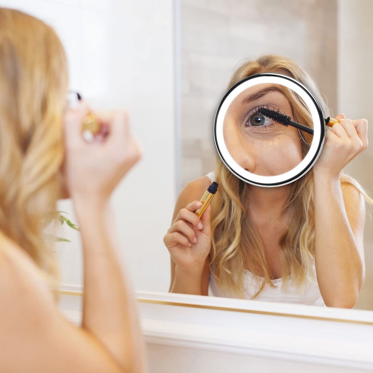 Donna usa uno specchio d'ingrandimento illuminato per il trucco.