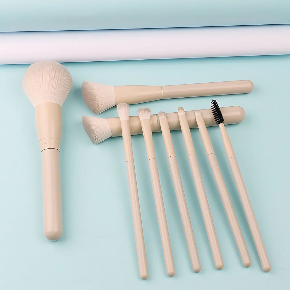 Un set di otto pennelli per il trucco beige chiaro con teste diverse, tra cui un grande pennello per cipria e pennelli più piccoli per occhi e labbra.