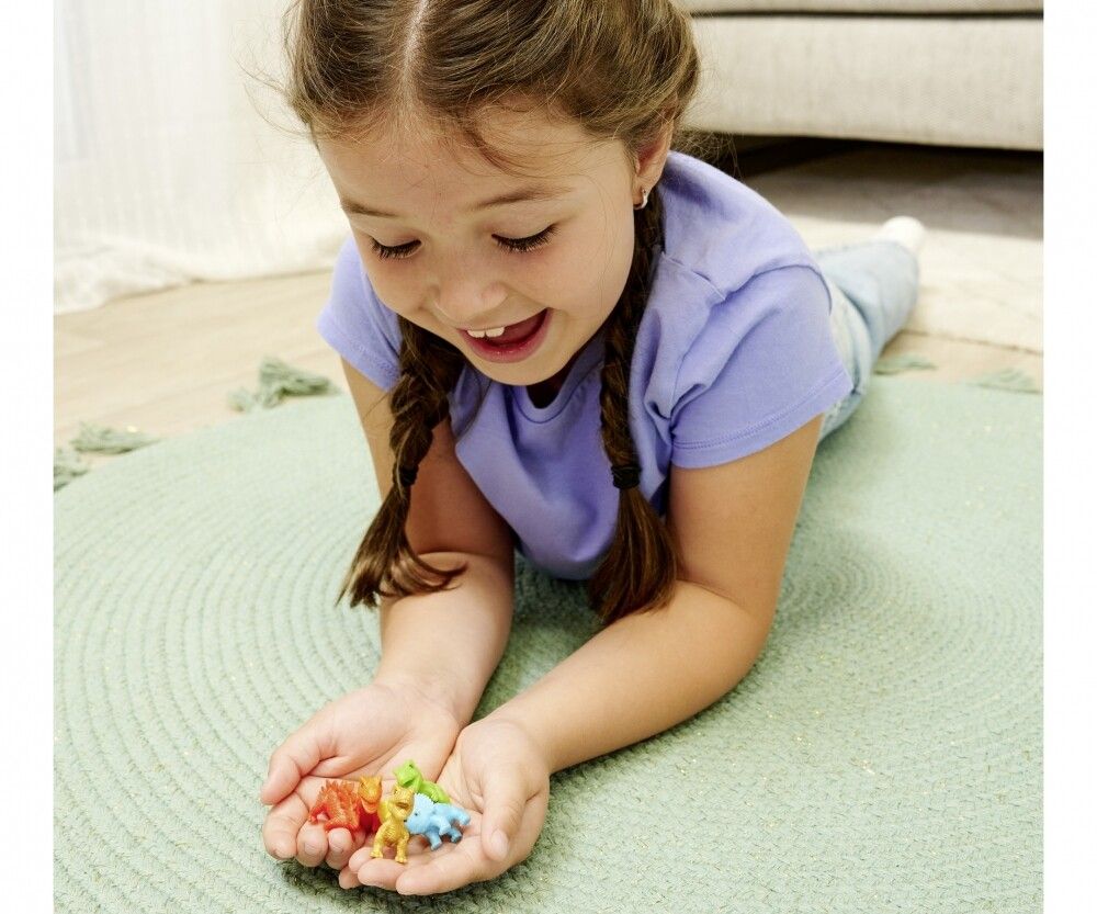 Bambina tiene in mano piccole figure di dinosauri. Vari colori.