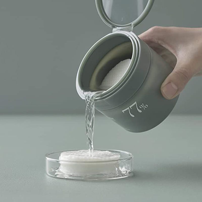 Mano che versa liquido da un barattolo verde su un pad. Scritta: 77%.