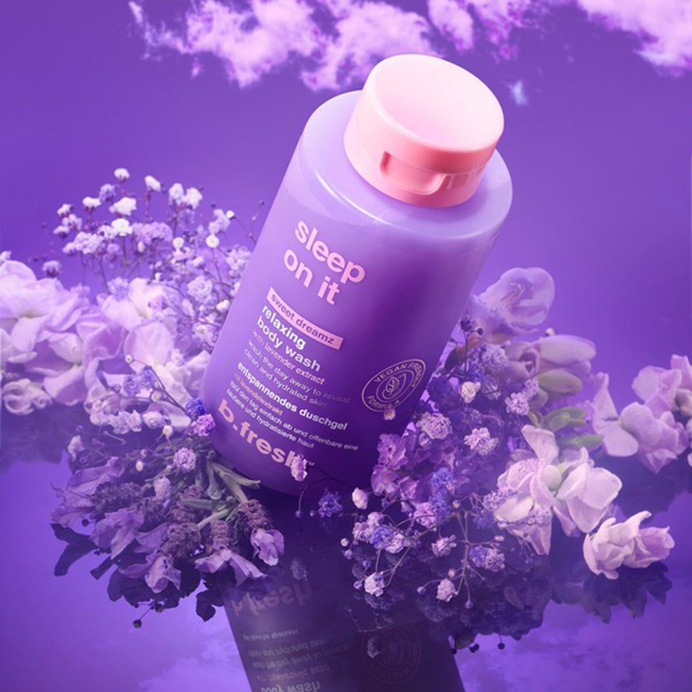 Flacone viola di bagnoschiuma rilassante "sleep on it", circondato da fiori viola e bianchi.