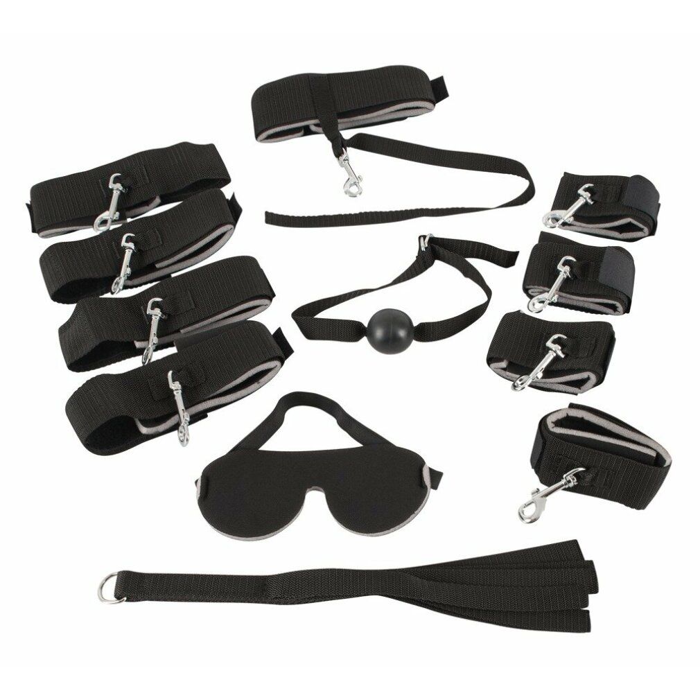 Set di accessori: maschera, manette, gag, frusta. Materiale nero con anelli e chiusure metalliche. Vista dall'alto.