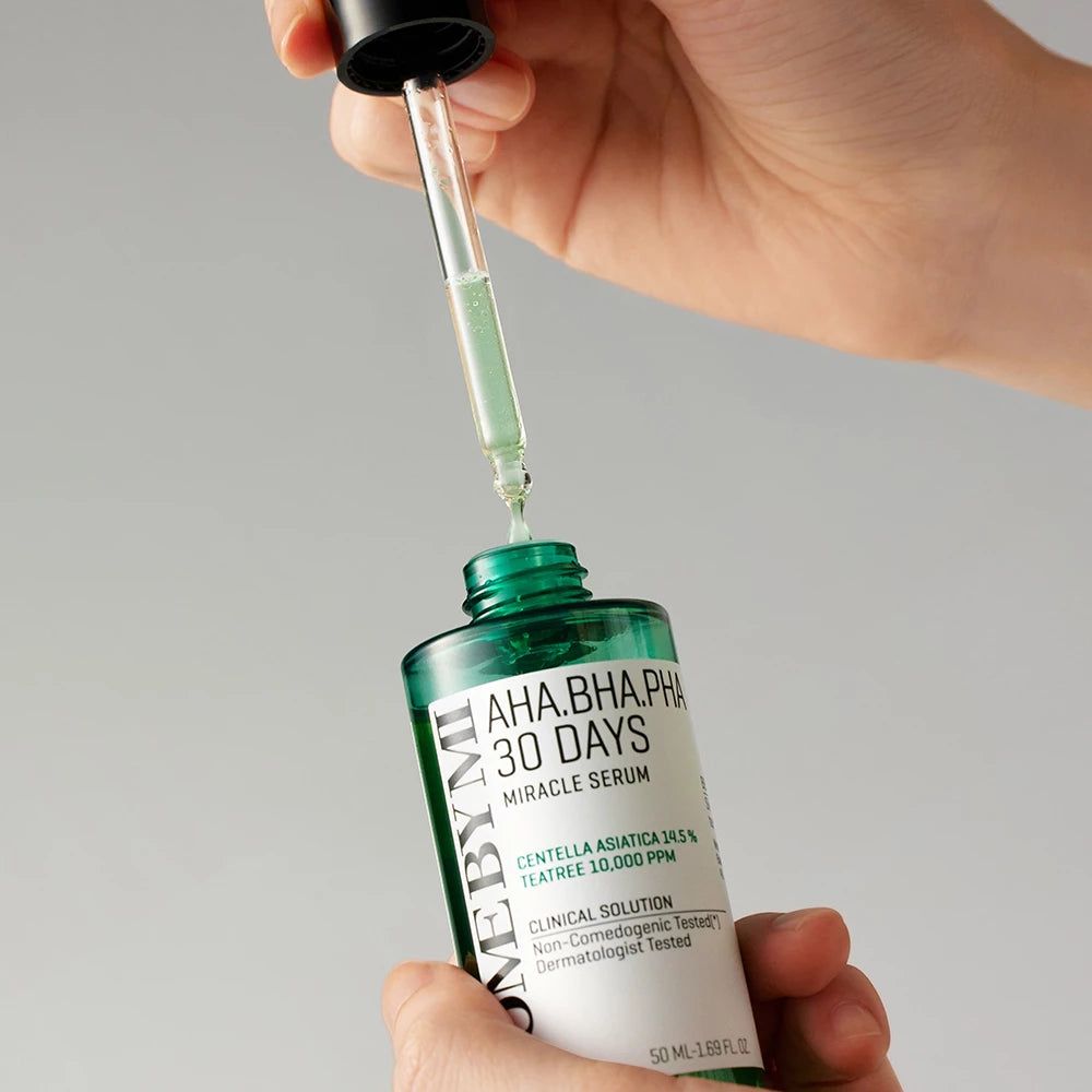 Mani che tengono un flacone di siero verde con pipetta. La pipetta preleva il siero. Scritta: AHA.BHA.PHA 30 DAYS MIRACLE SERUM.