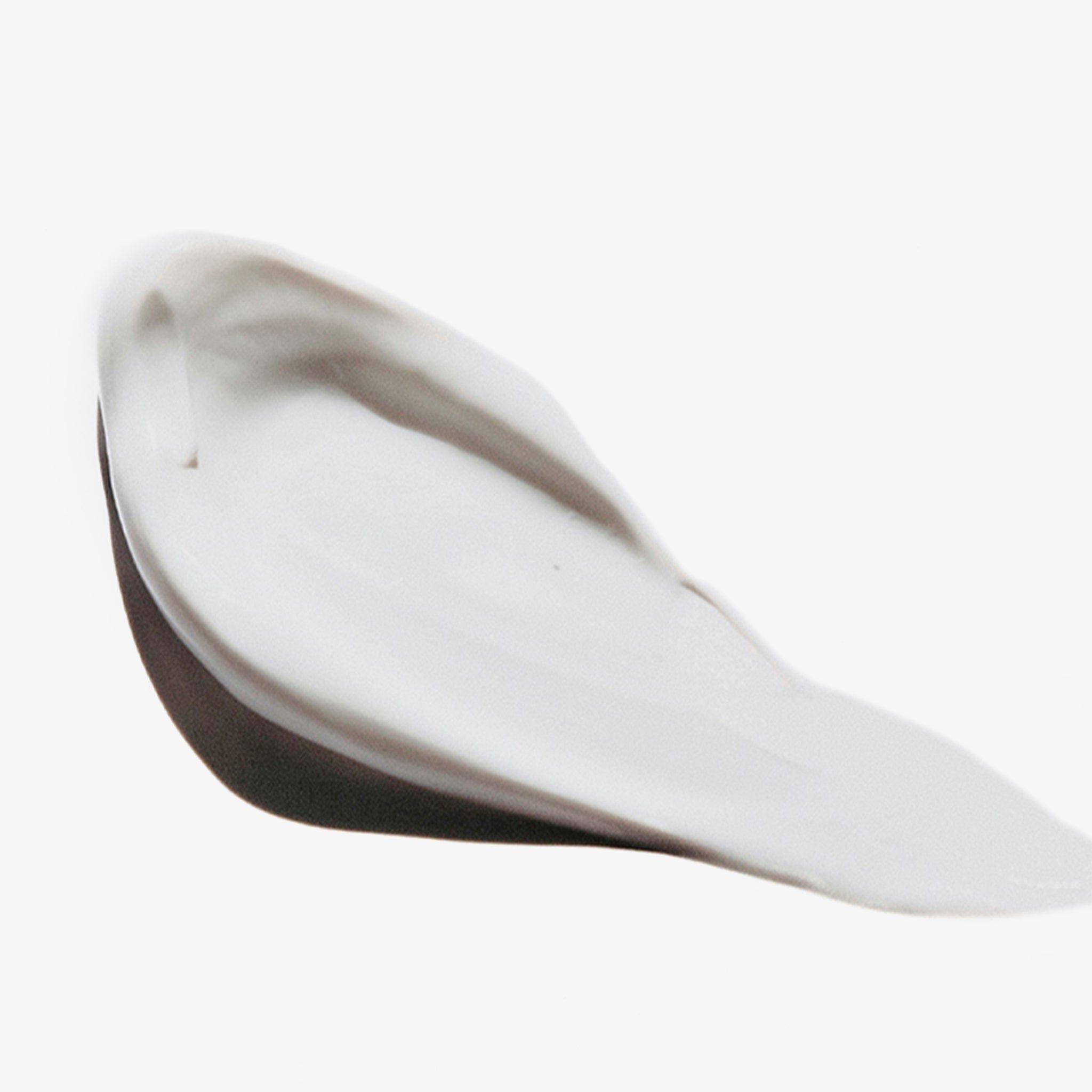 Macchia di balsamo bianco su sfondo bianco. Texture liscia, leggermente lucida.
