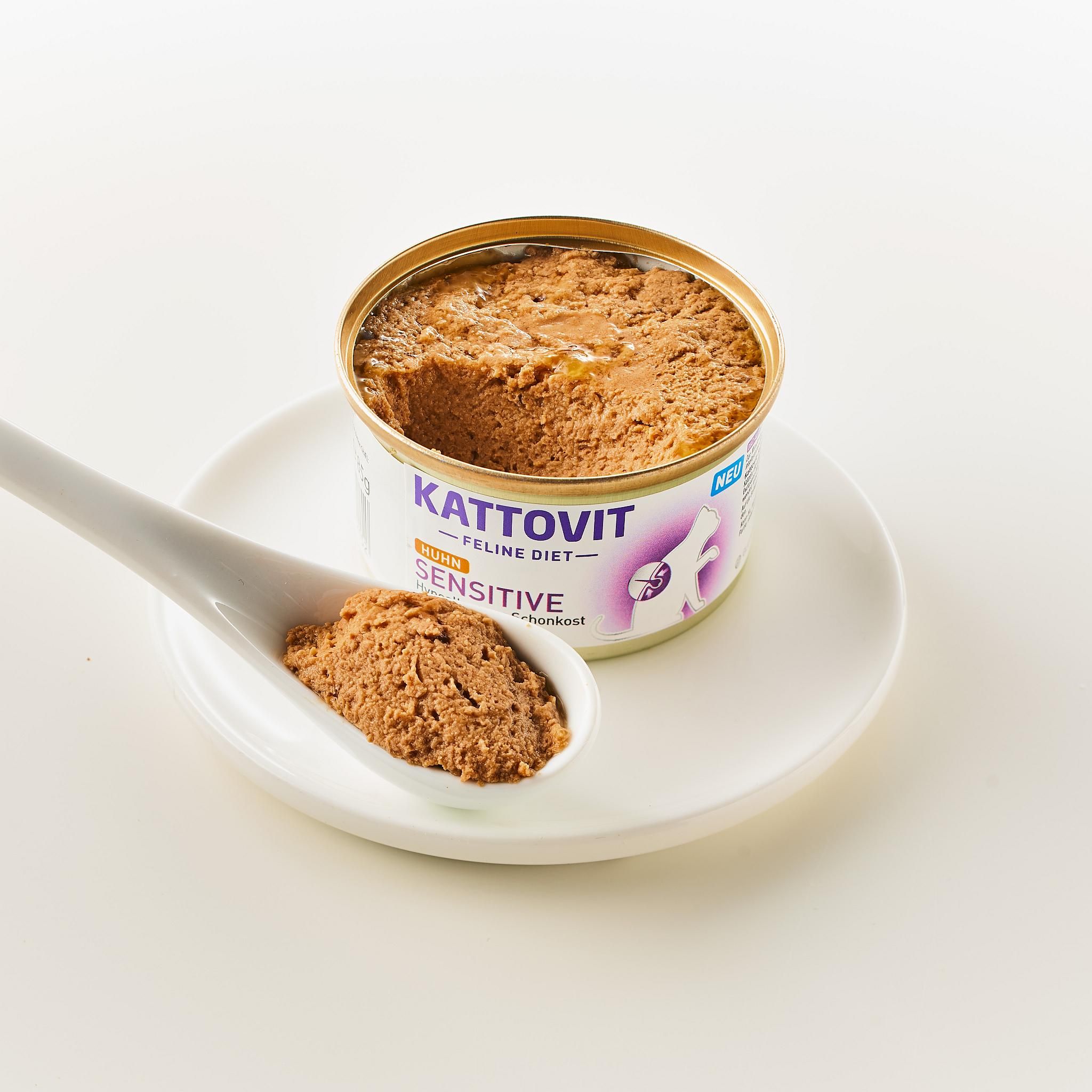 Lattina Kattovit Sensitive Huhn aperta con cibo. Cucchiaio con cibo accanto. Lattina su piatto bianco.