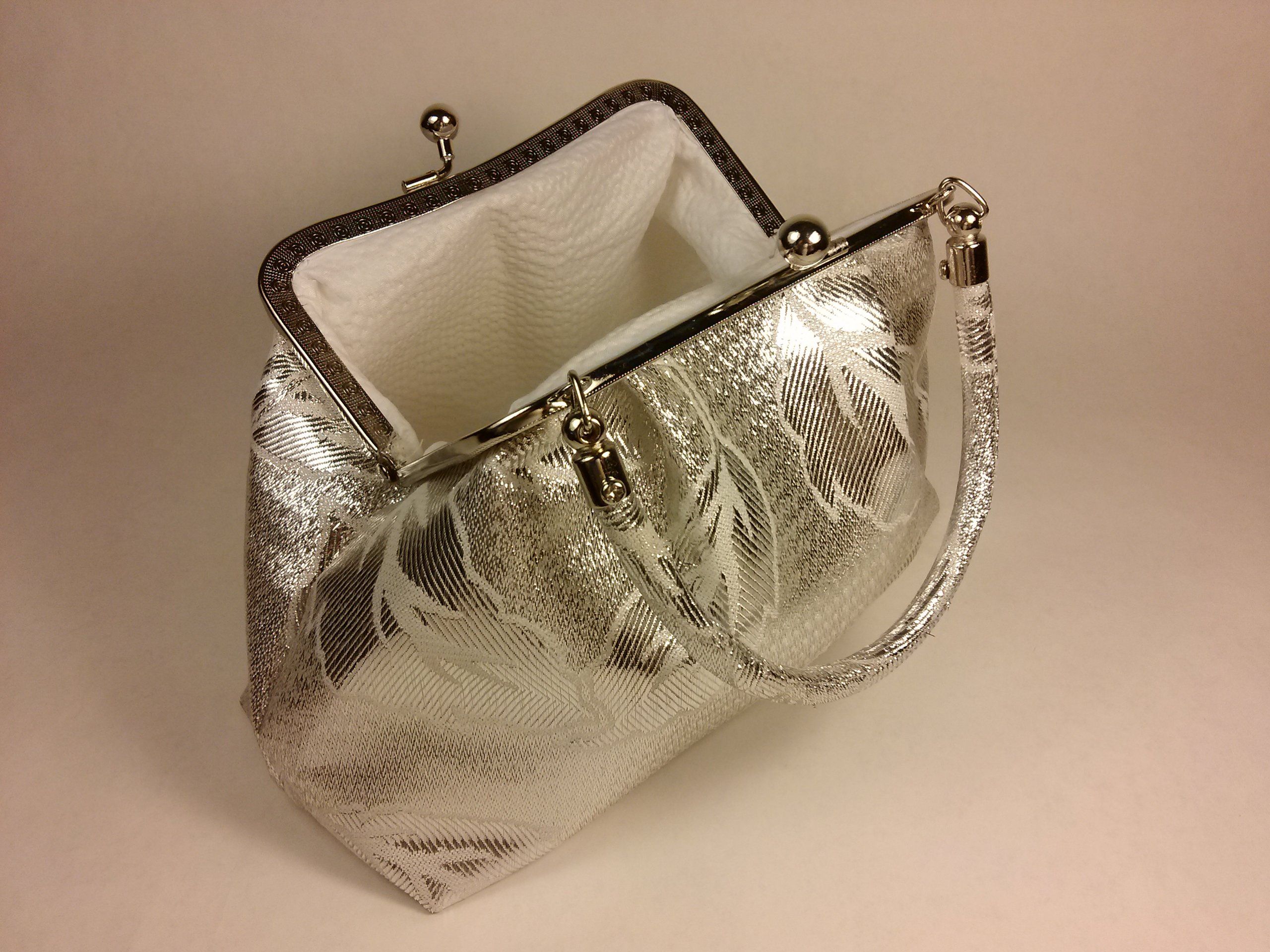 Borsa argentata con motivo floreale. Aperta, con manico.