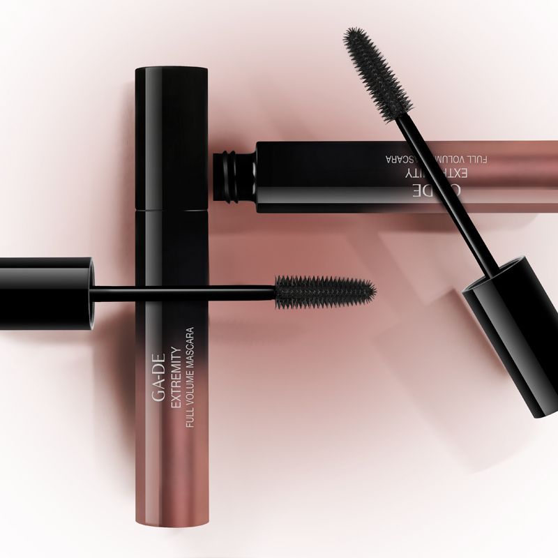 Tre tubi di mascara. Due con spazzole estratte. Scritta: GA-DE Extremity Full Volume Mascara. Sfondo rosa.