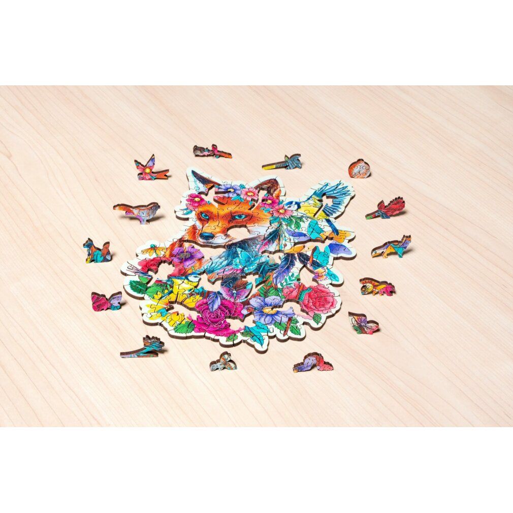 Puzzle in legno con motivo volpe e pezzi singoli. Volpe con corona di fiori, uccelli e farfalle. Pezzi sparsi su superficie in legno.